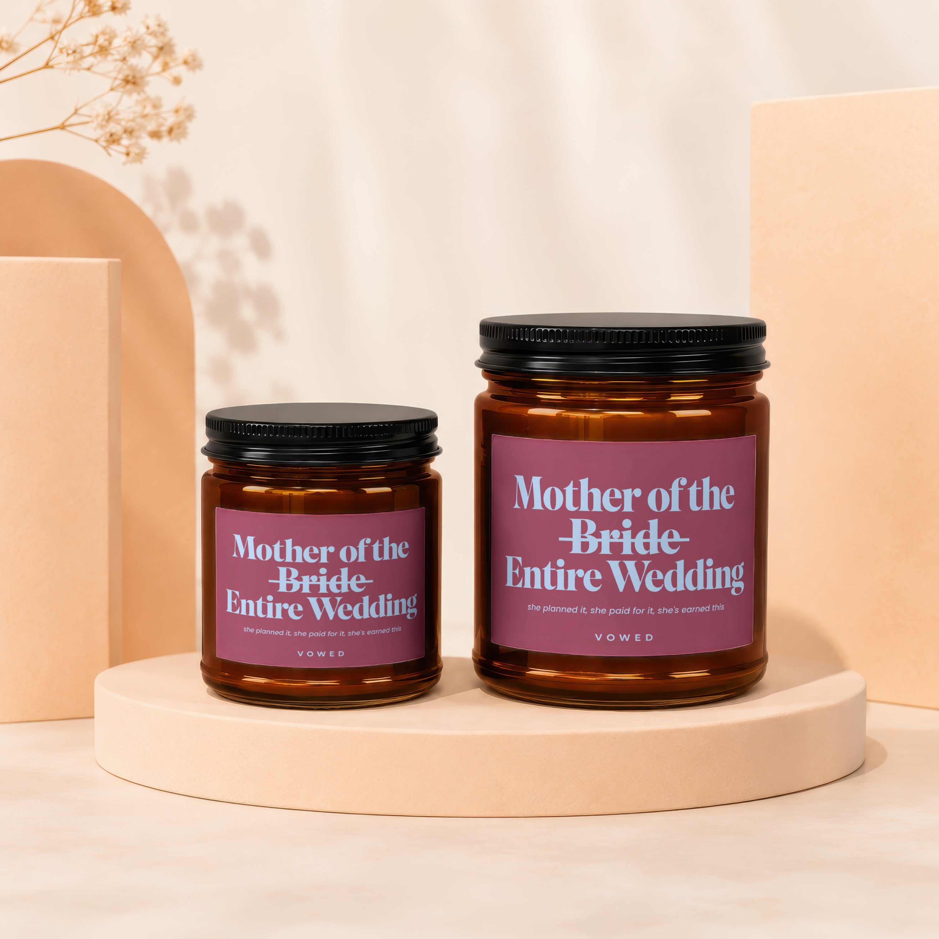 Two amber glass candles with pink labels reading "Mother of the Bride-Entire Wedding."