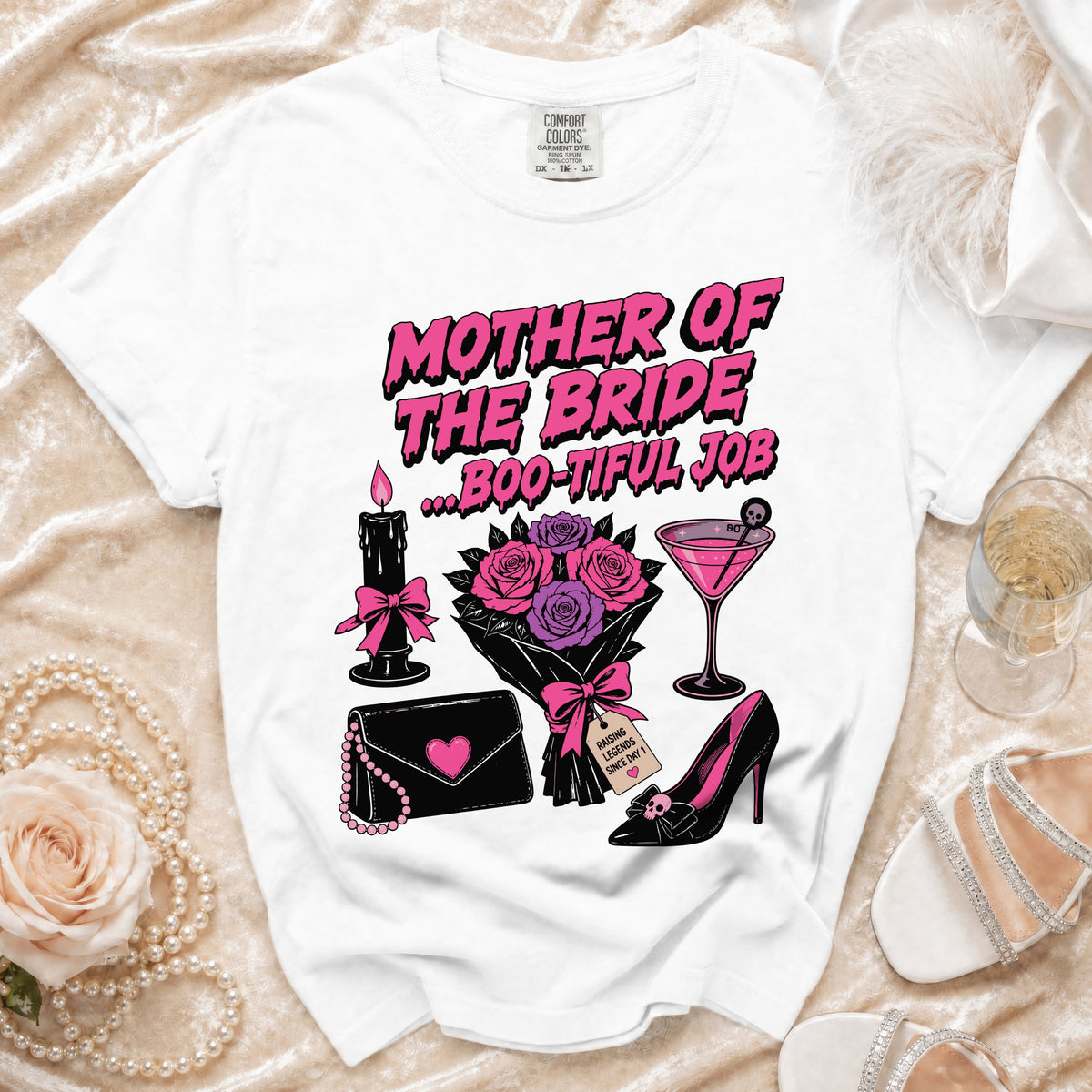 A white t-shirt featuring pink text that reads Mother of the Bride ... Boo-Tiful Job, surrounded by gothic-style illustrations.