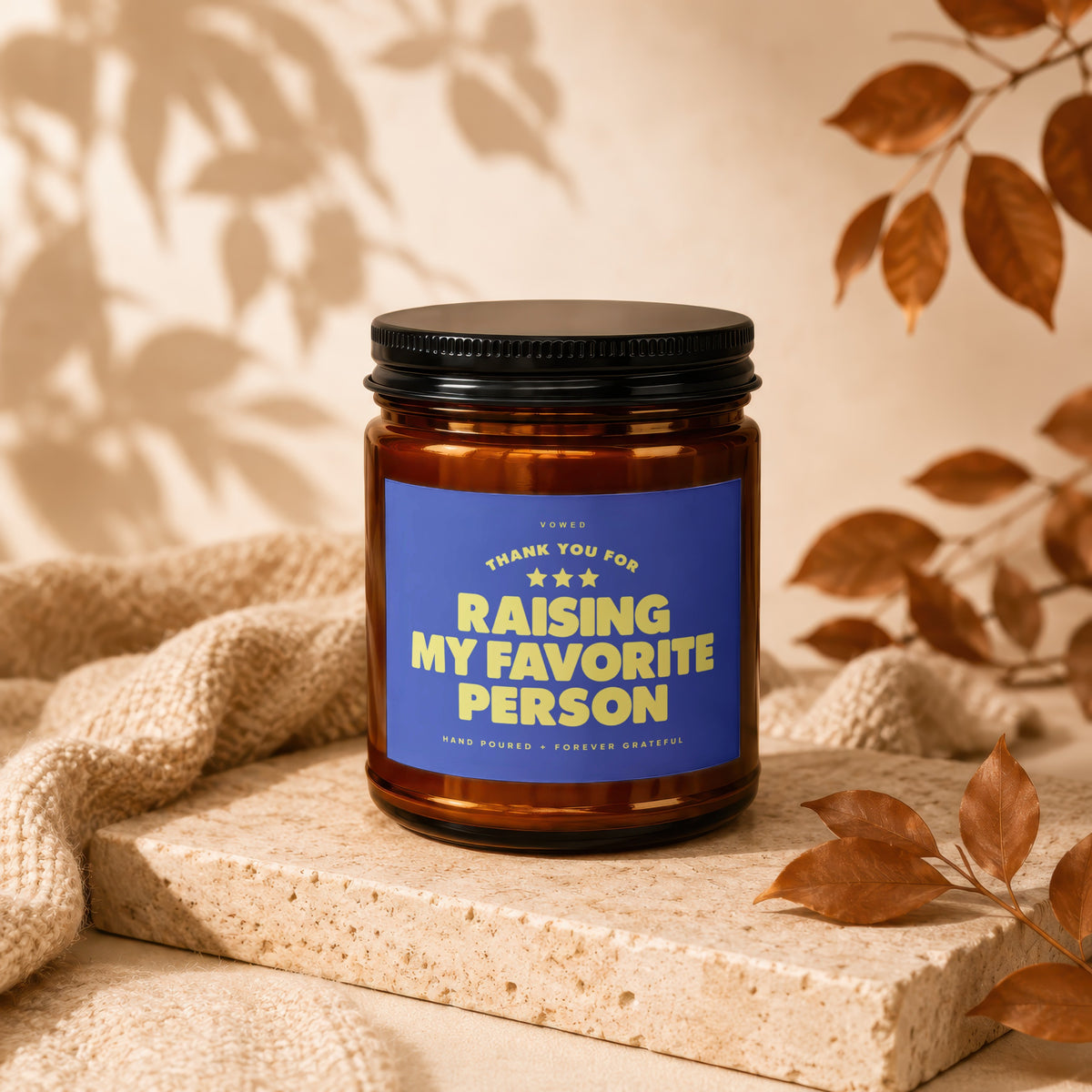 Amber jar candle with blue label reading "Raising My Favorite Person"