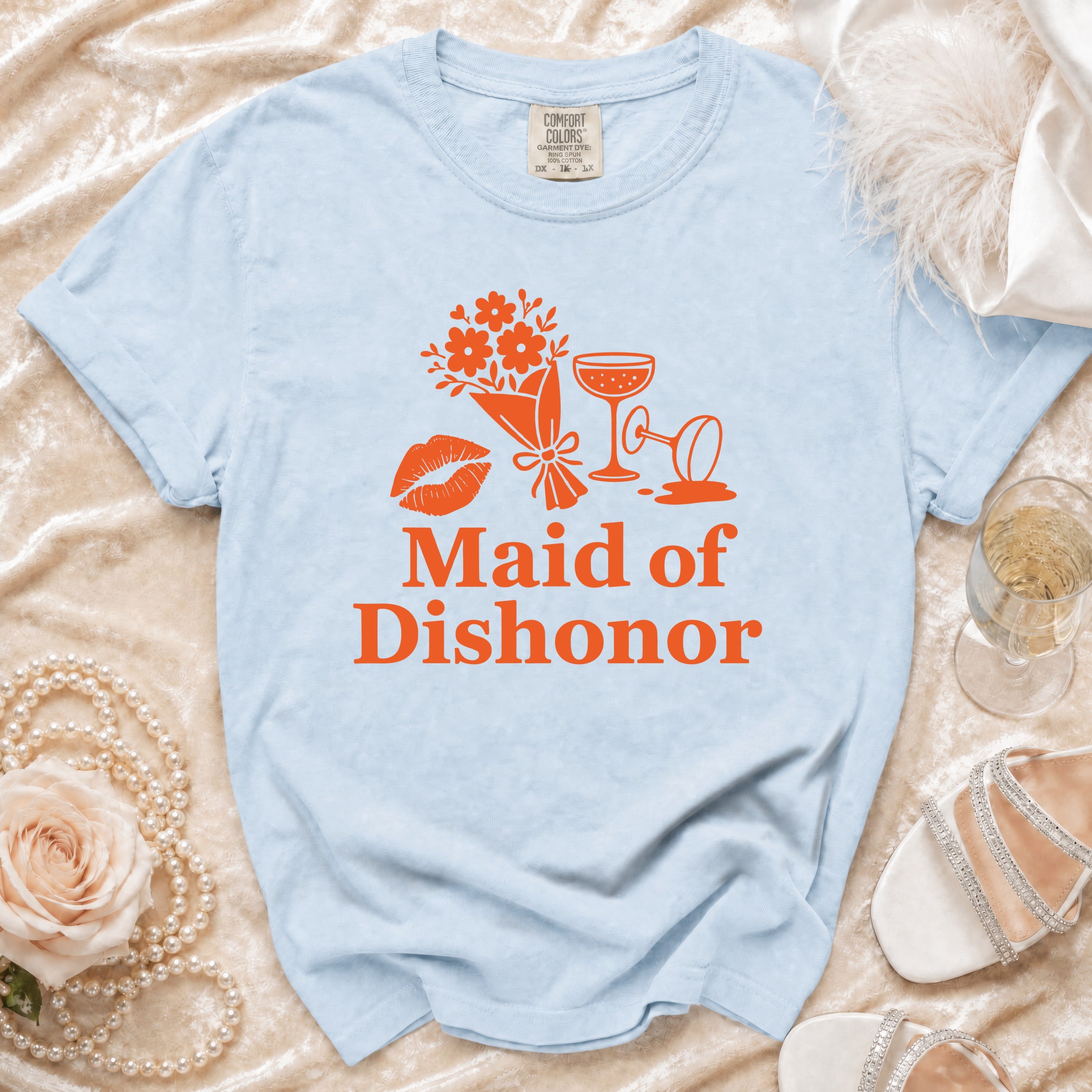 Light blue t-shirt with orange "Maid of Dishonor" text, flowers, lips, and champagne glasses.