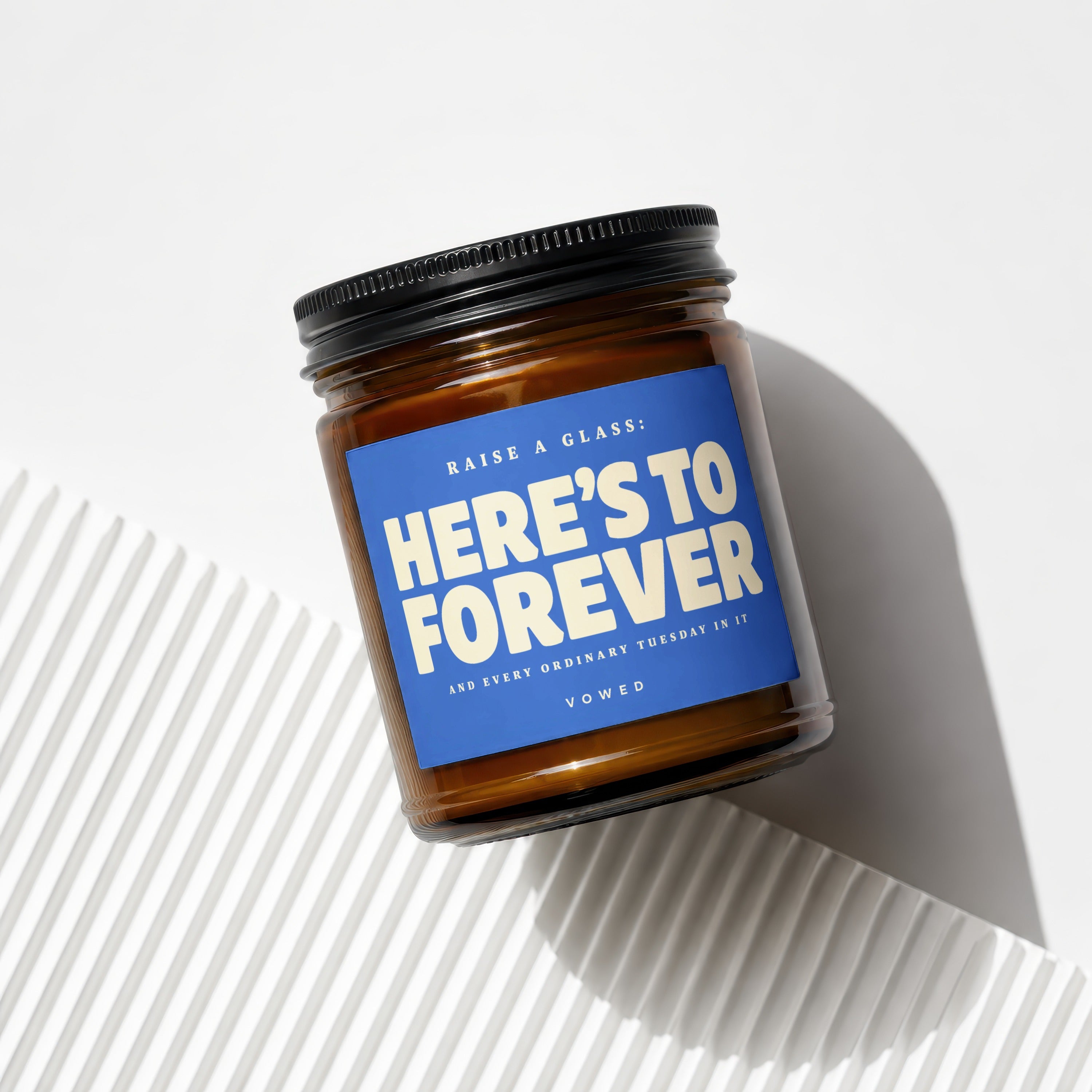 Amber jar candle with a blue label that reads "Here's to forever".