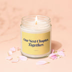 Lit candle in a glass jar with yellow label reading "Our Next Chapter, Together."