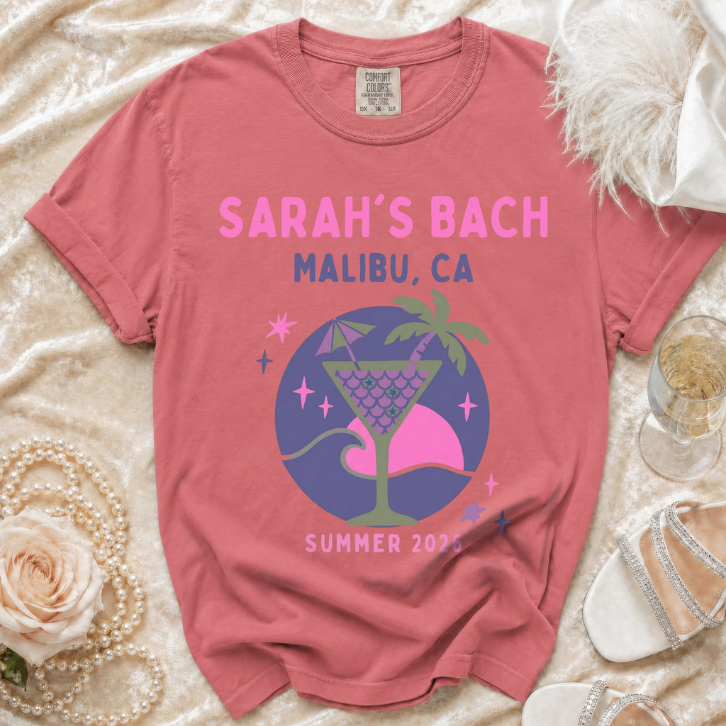 Pink graphic tee with "SARAH'S BACH MALIBU, CA SUMMER 2026" and a cocktail design.