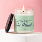 Glass jar candle with lit wick and black lid, featuring text "WITNESS TO the Ritual VOWED".