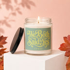 Scented candle with "We Both Said Yes" text on label, lid off, autumn leaves decor.