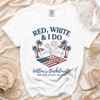 White t-shirt with "Red, White & I Do" text, American flag, fireworks, and palm trees.