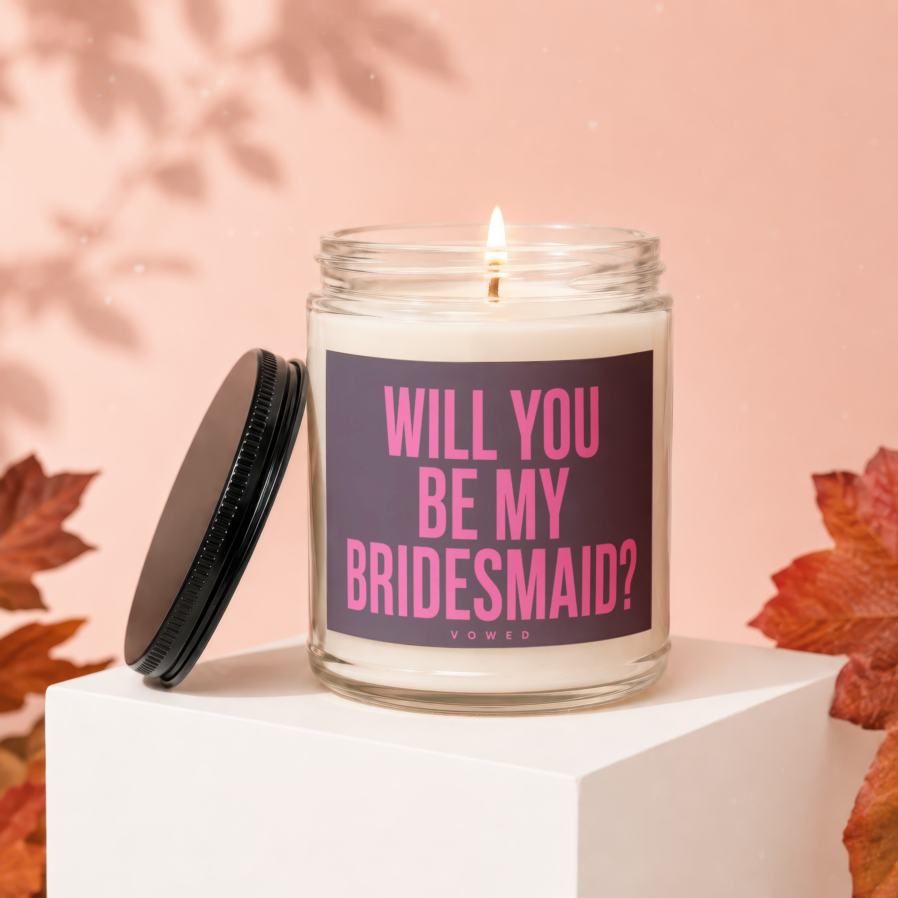 Glass candle with pink text "WILL YOU BE MY BRIDESMAID?" on dark purple label.