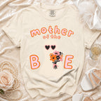 Cream t-shirt with "mother of the B E" ghost graphic and bouquet.