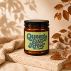 Amber jar candle with "Queerly Ever After VOWED" text on a light green label.