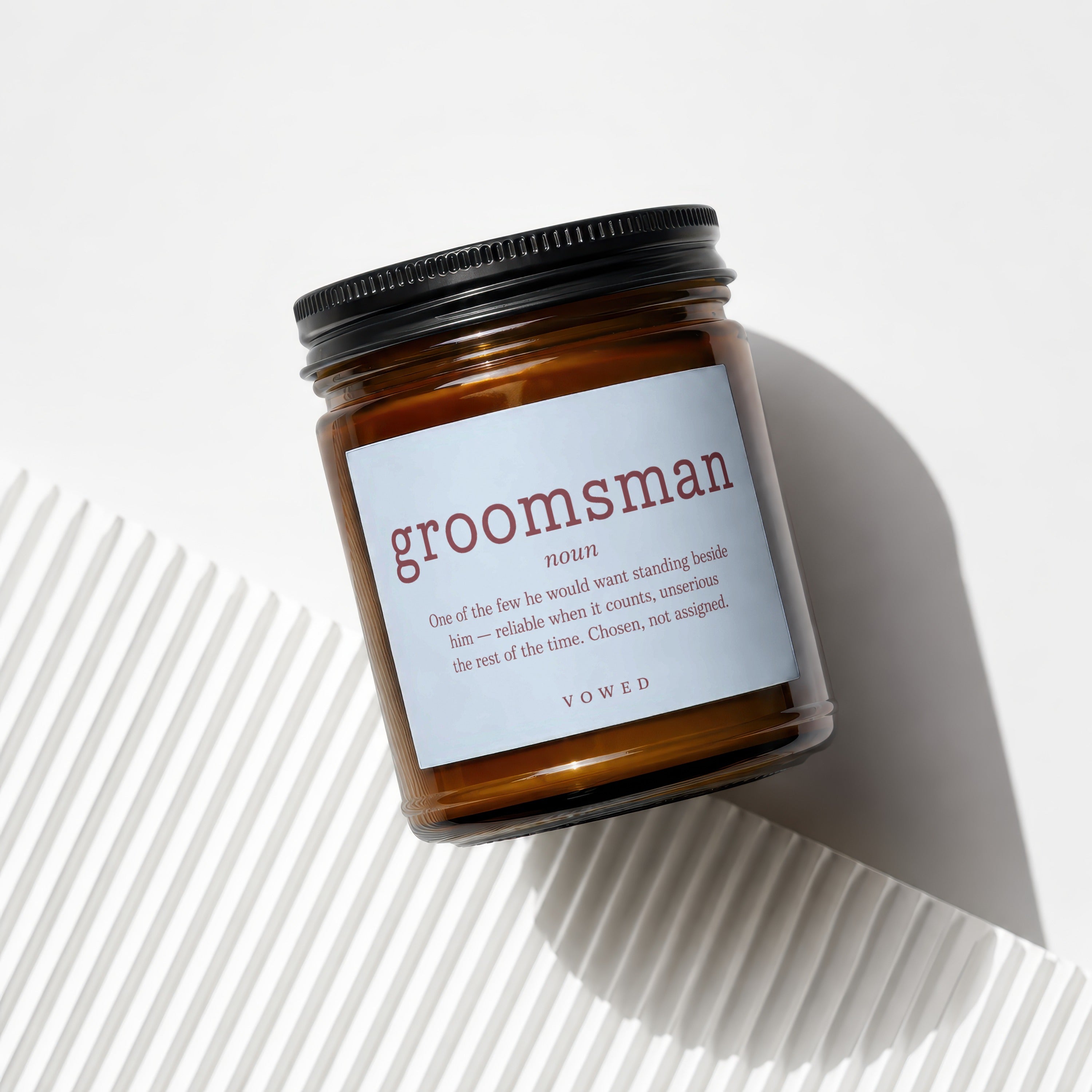 Amber jar candle with black lid labeled "groomsman noun" and a definition.