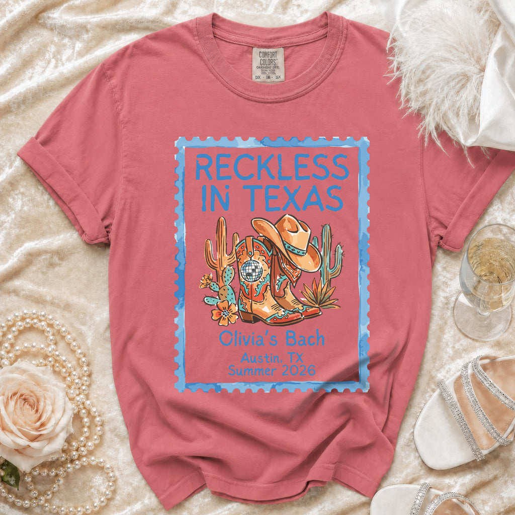 Coral t-shirt with "Reckless in Texas" and cowboy boot graphic.
