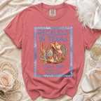 Coral t-shirt with "Reckless in Texas" and cowboy boot graphic.