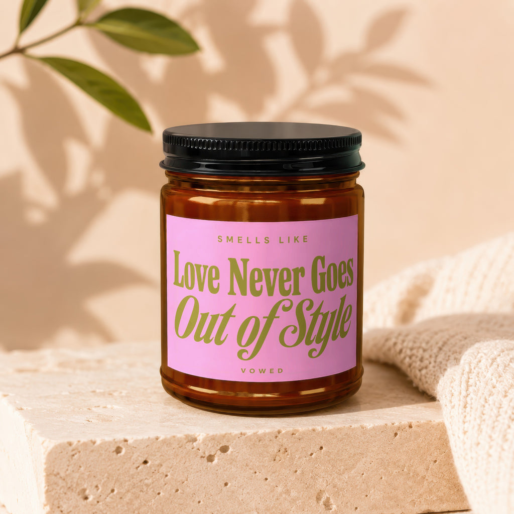 Candle with pink label reading "Smells Like Love Never Goes Out of Style Vowed".