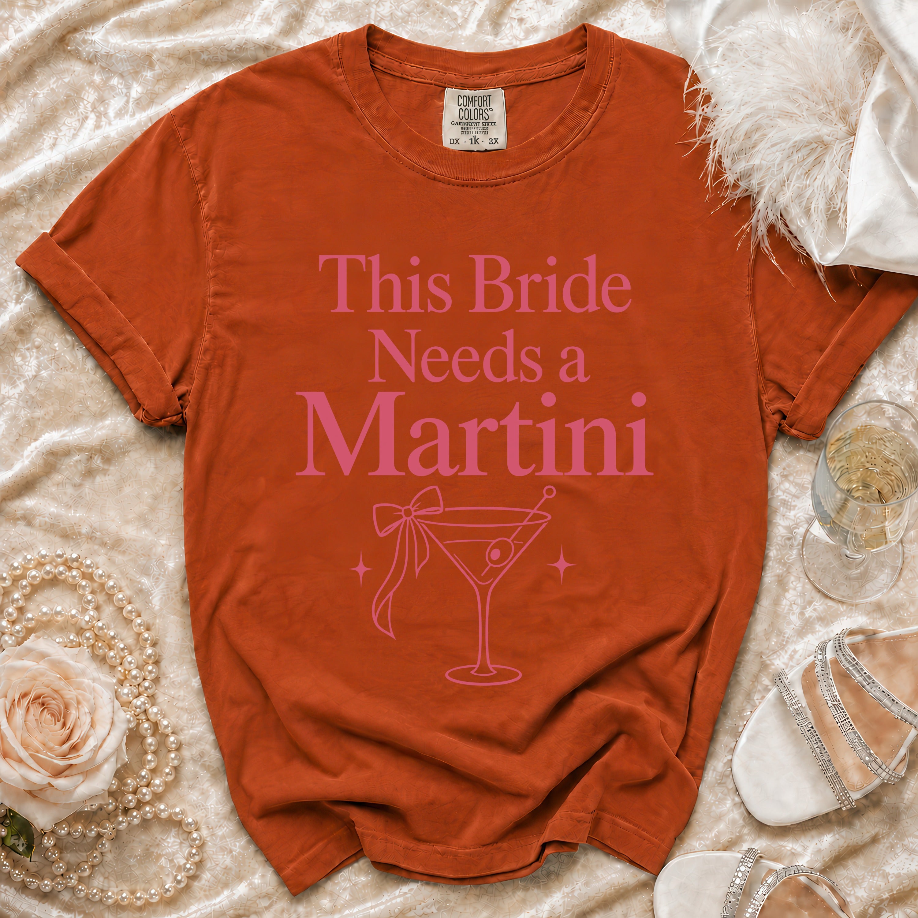 Orange Comfort Colors t-shirt with pink "This Bride Needs a Martini" text and martini glass graphic.