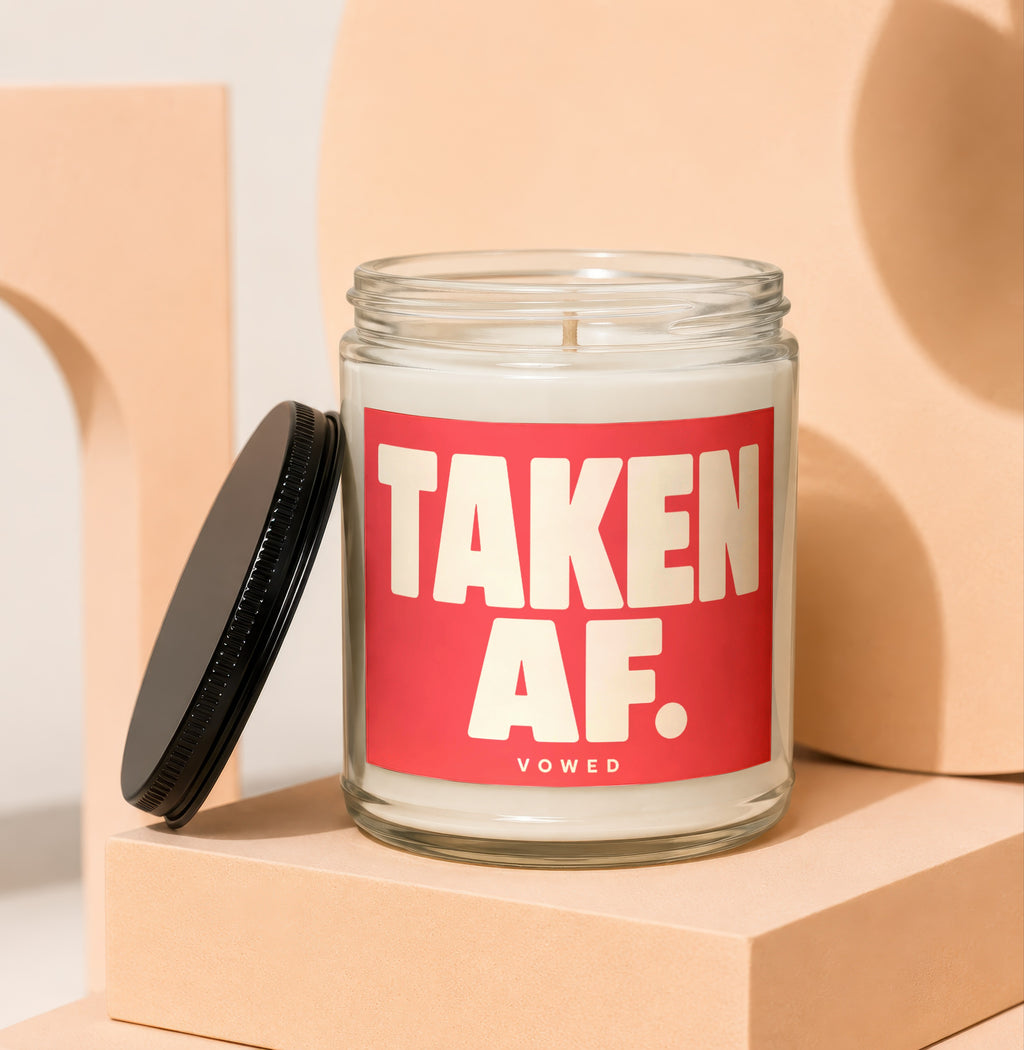 Glass candle with red label reading "TAKEN AF." and "VOWED".