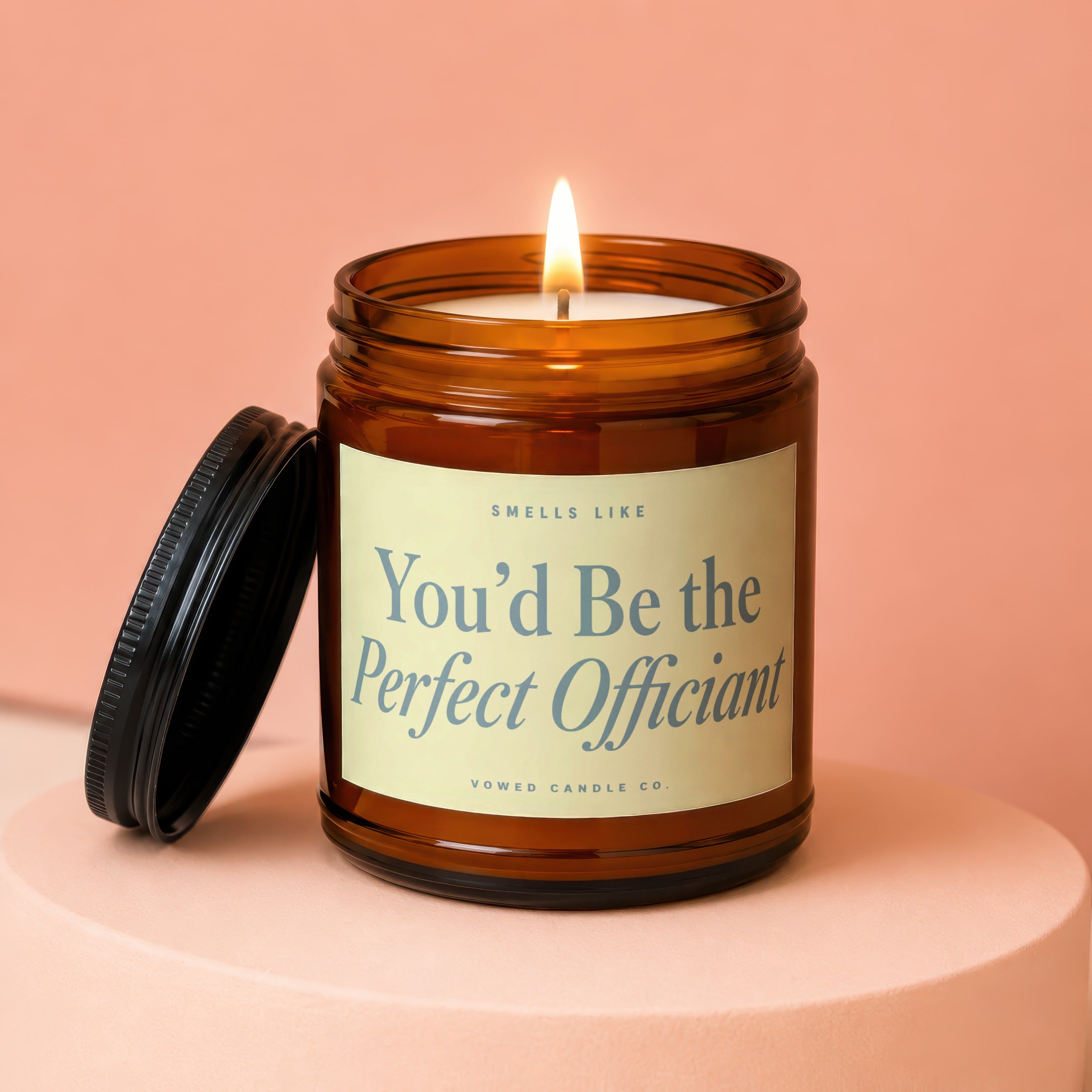Amber jar candle with lit wick and label that reads "You'd Be the Perfect Officiant."
