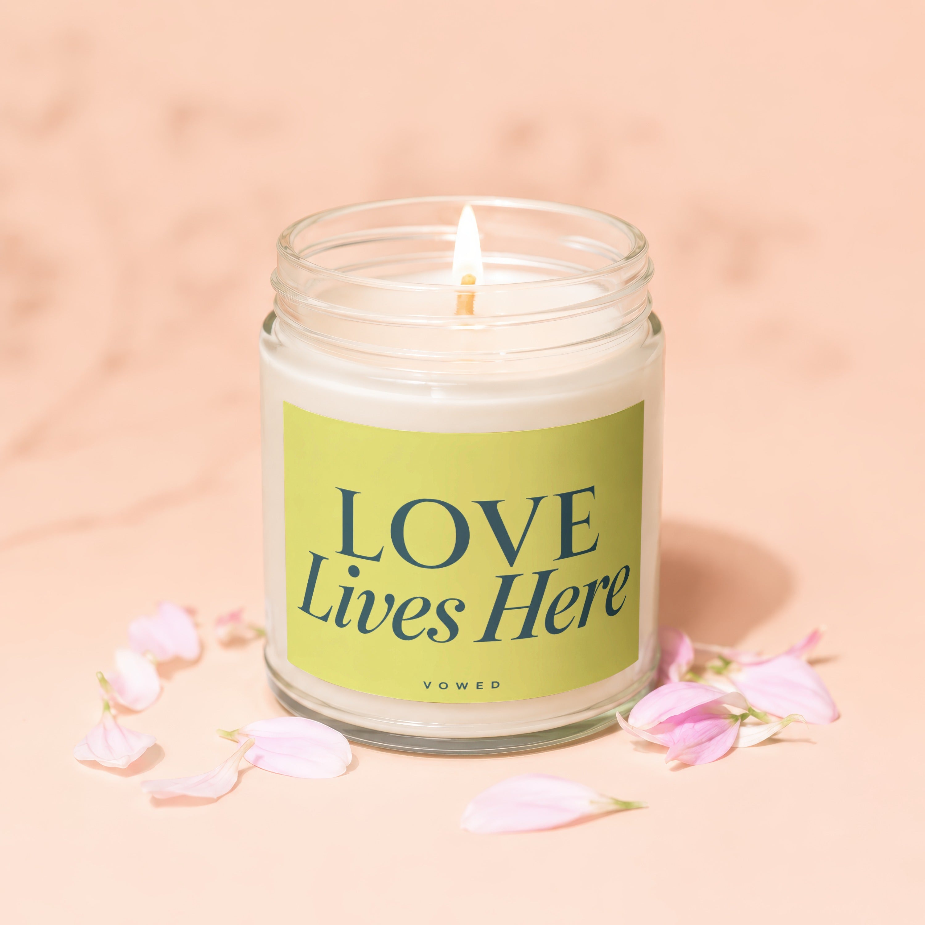 Jar candle with lit flame and green label that reads "LOVE Lives Here"
