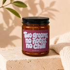 Amber candle in glass jar with black lid, label reads "Two grooms, no notes, no chill VOWED".