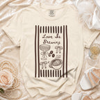 Cream t-shirt with "Love Is Brewing" and coffee graphics, 2026.