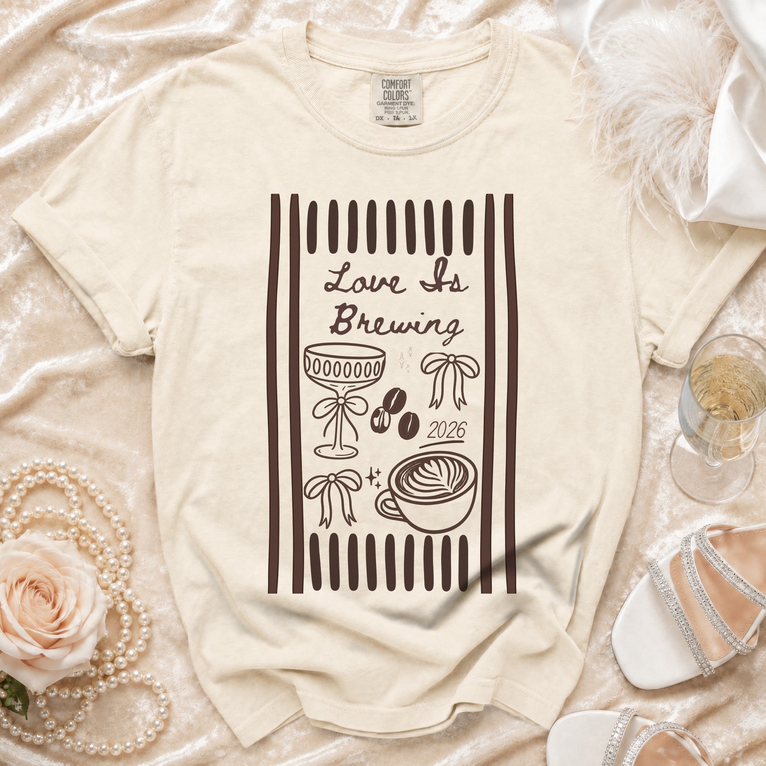 Cream t-shirt with "Love Is Brewing" and coffee graphics, 2026.