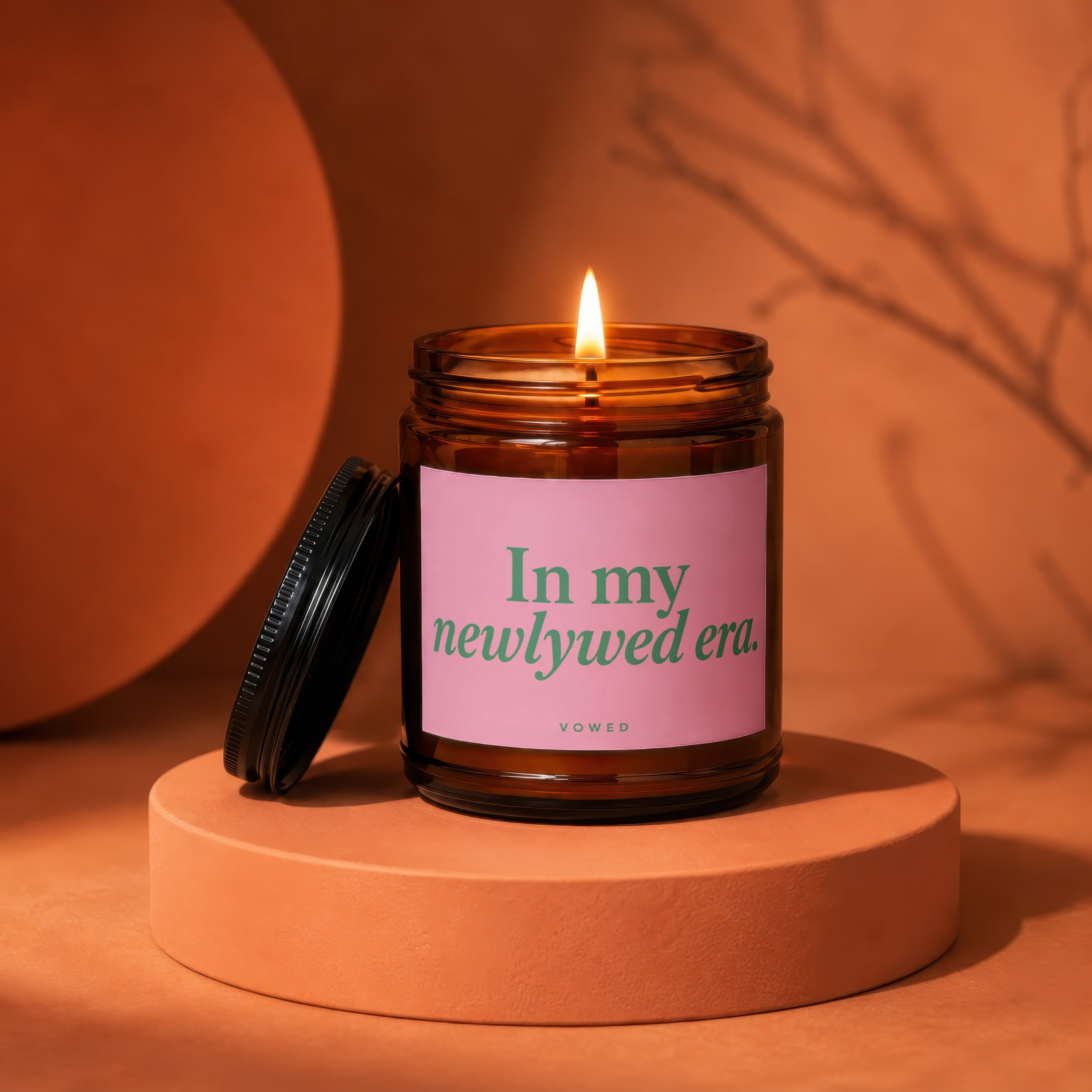Amber jar candle with pink label reading "In my newlywed era." Vowed.