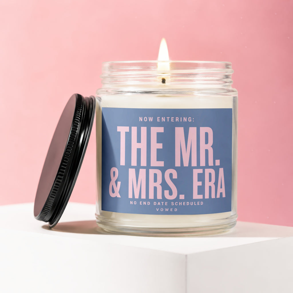 Glass candle with lit wick and lid, reads "The Mr. & Mrs. Era".