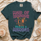 Maid of Honour Needs a Mimosa text on a dark green t-shirt.