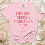 Pink t-shirt with "This girl needs a margarita" text and margarita graphic.