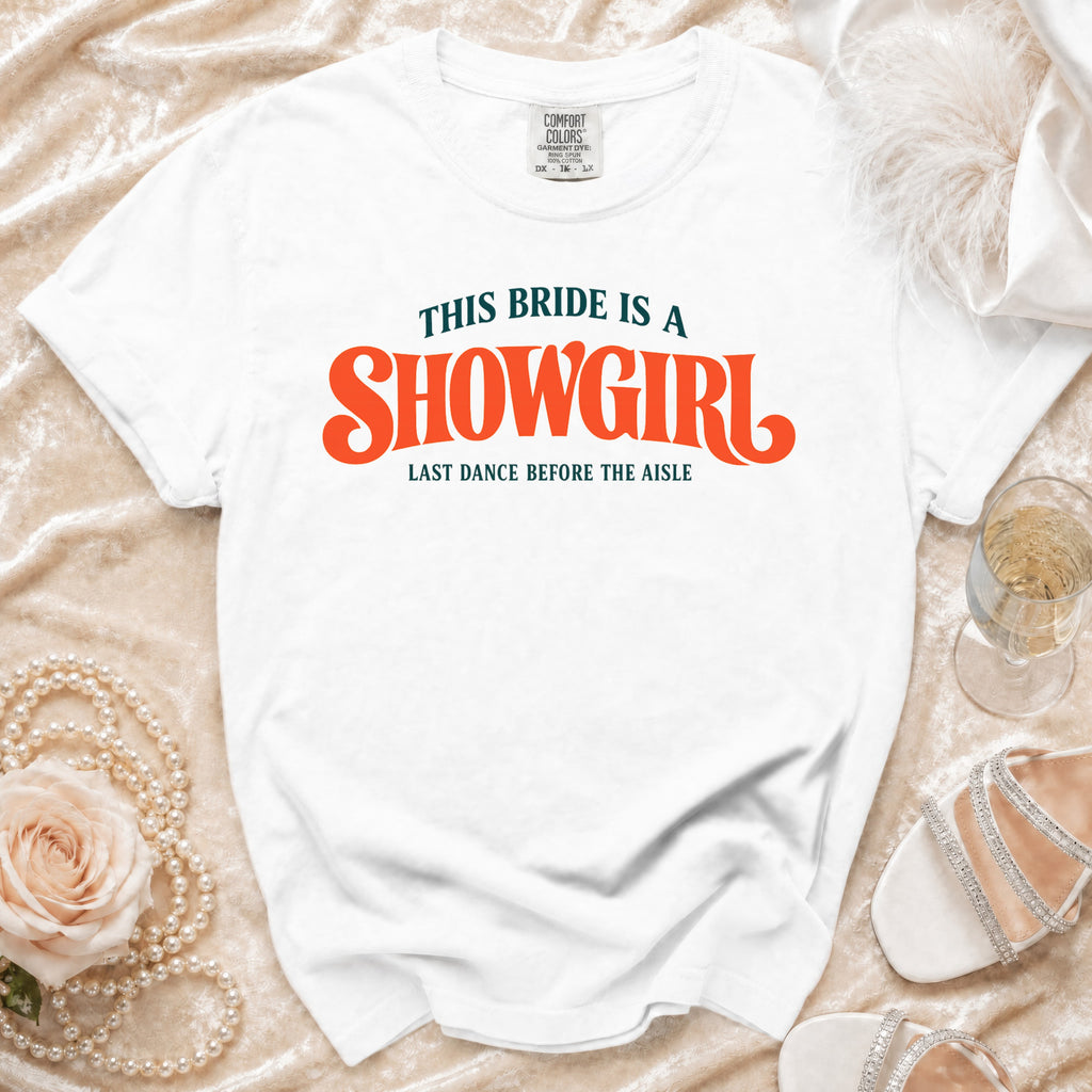 White t-shirt with text "THIS BRIDE IS A SHOWGIRL LAST DANCE BEFORE THE AISLE".