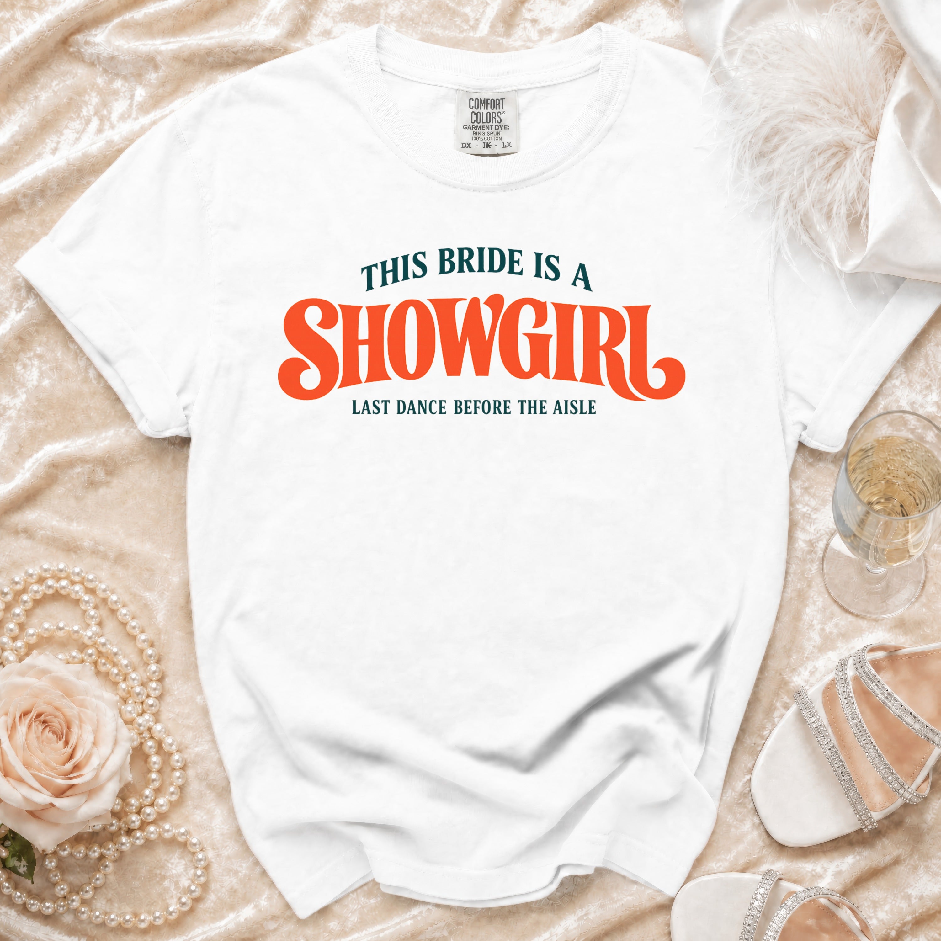 White t-shirt with text "THIS BRIDE IS A SHOWGIRL LAST DANCE BEFORE THE AISLE".