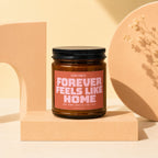 Candle with label "CONFIRMED: FOREVER FEELS LIKE HOME AND HOME SMELLS LIKE THIS".