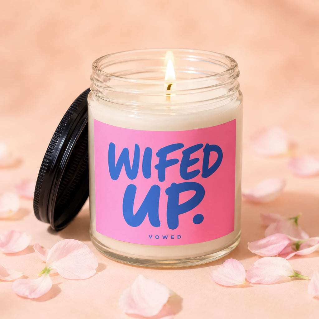 Candle with "WIFED UP" text on a pink label, surrounded by petals.