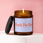 Amber candle with burning flame and black lid, labeled "Worth The Wait."