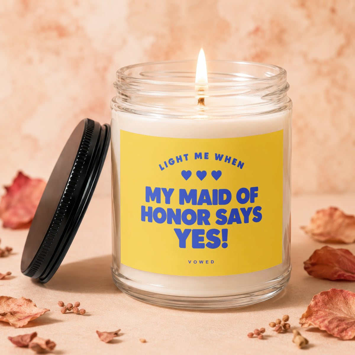 Glass candle with yellow label reading "Light me when my maid of honor says yes!".