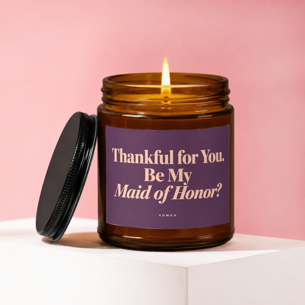 Amber jar candle with lit flame, lid off, and text: "Thankful for You. Be My Maid of Honor? VOWED"