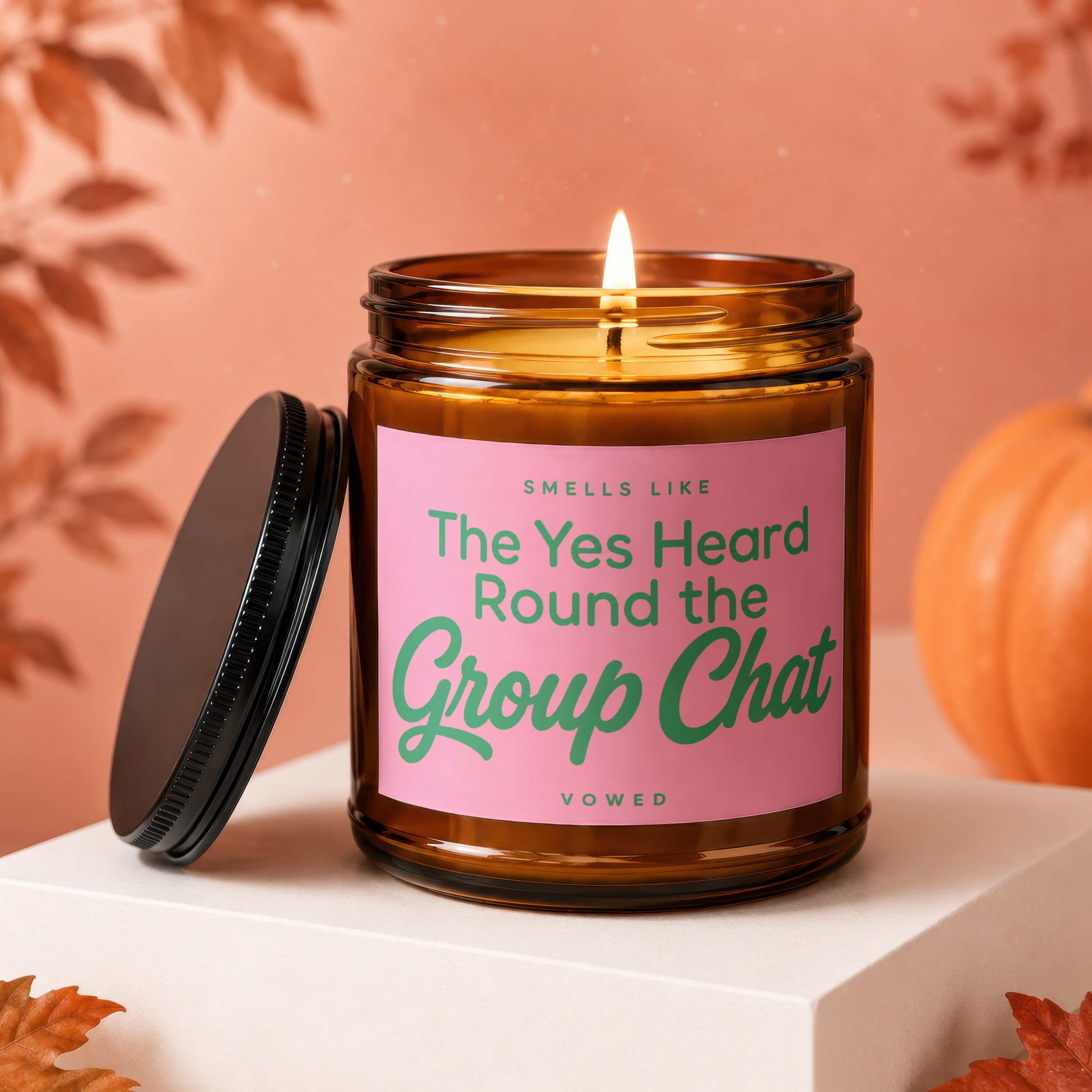 Amber jar candle with pink label reading "Smells Like The Yes Heard Round the Group Chat".