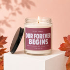 Candle with text "Our Forever Begins" on a dusky rose background.