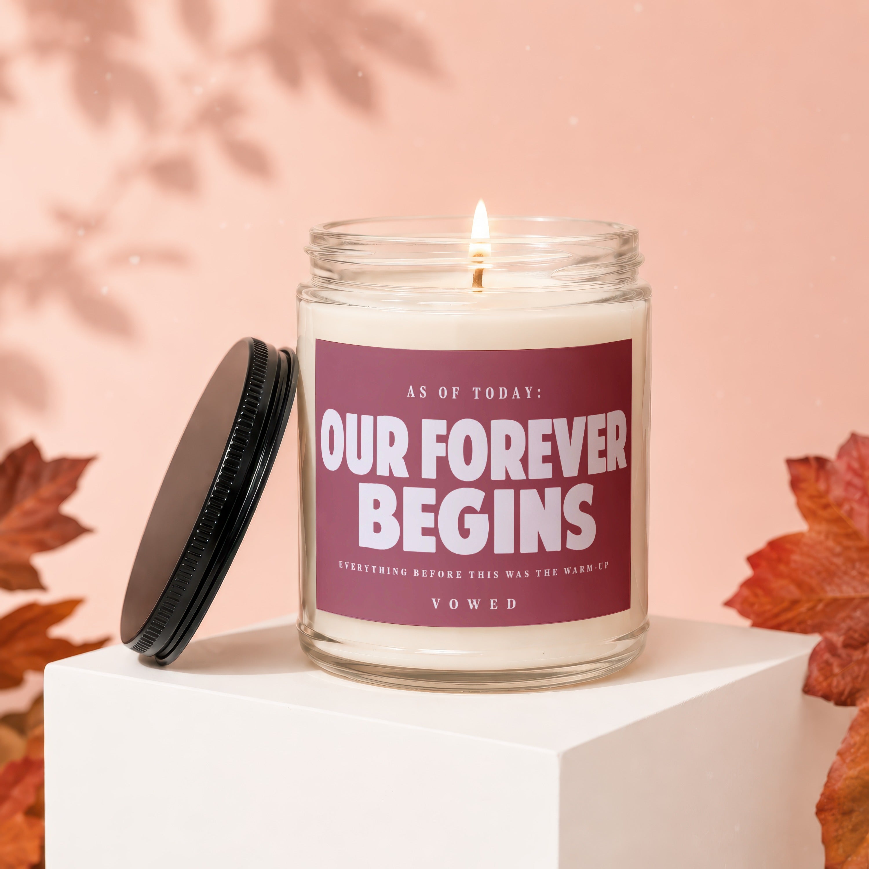 Candle with text "Our Forever Begins" on a dusky rose background.