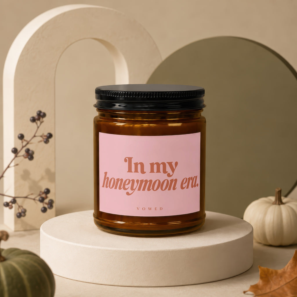 Amber candle with a pink label saying "In my honeymoon era. VOWED".