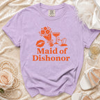 Purple t-shirt with orange text "Maid of Dishonor," lips, flowers, and champagne glasses.