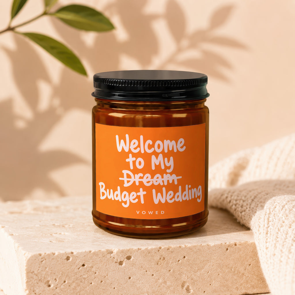 Candle with orange label reading "Welcome to My Dream Budget Wedding".