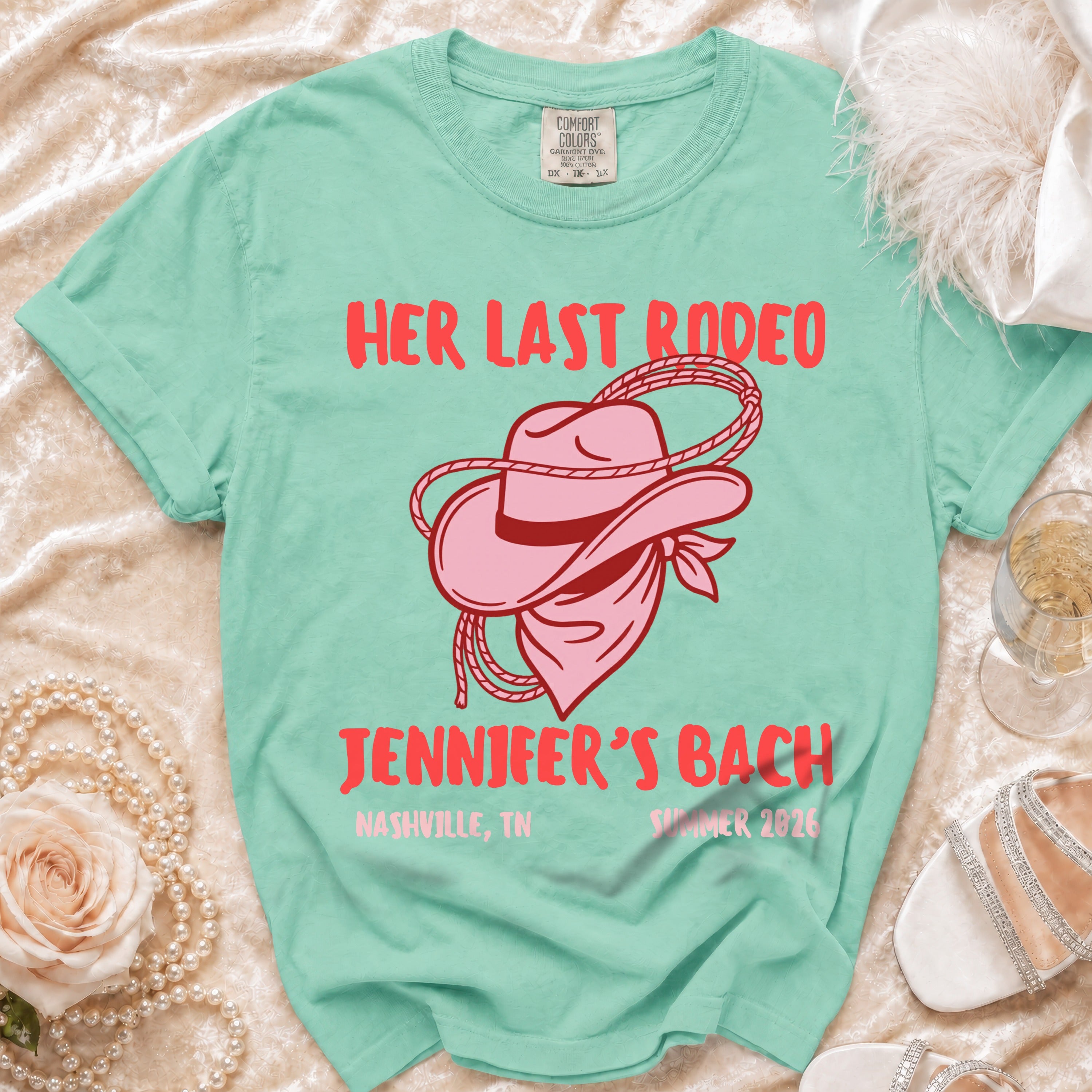 Pink cowboy hat and bandana graphic on a teal "Her Last Rodeo Jennifer's Bach" t-shirt.