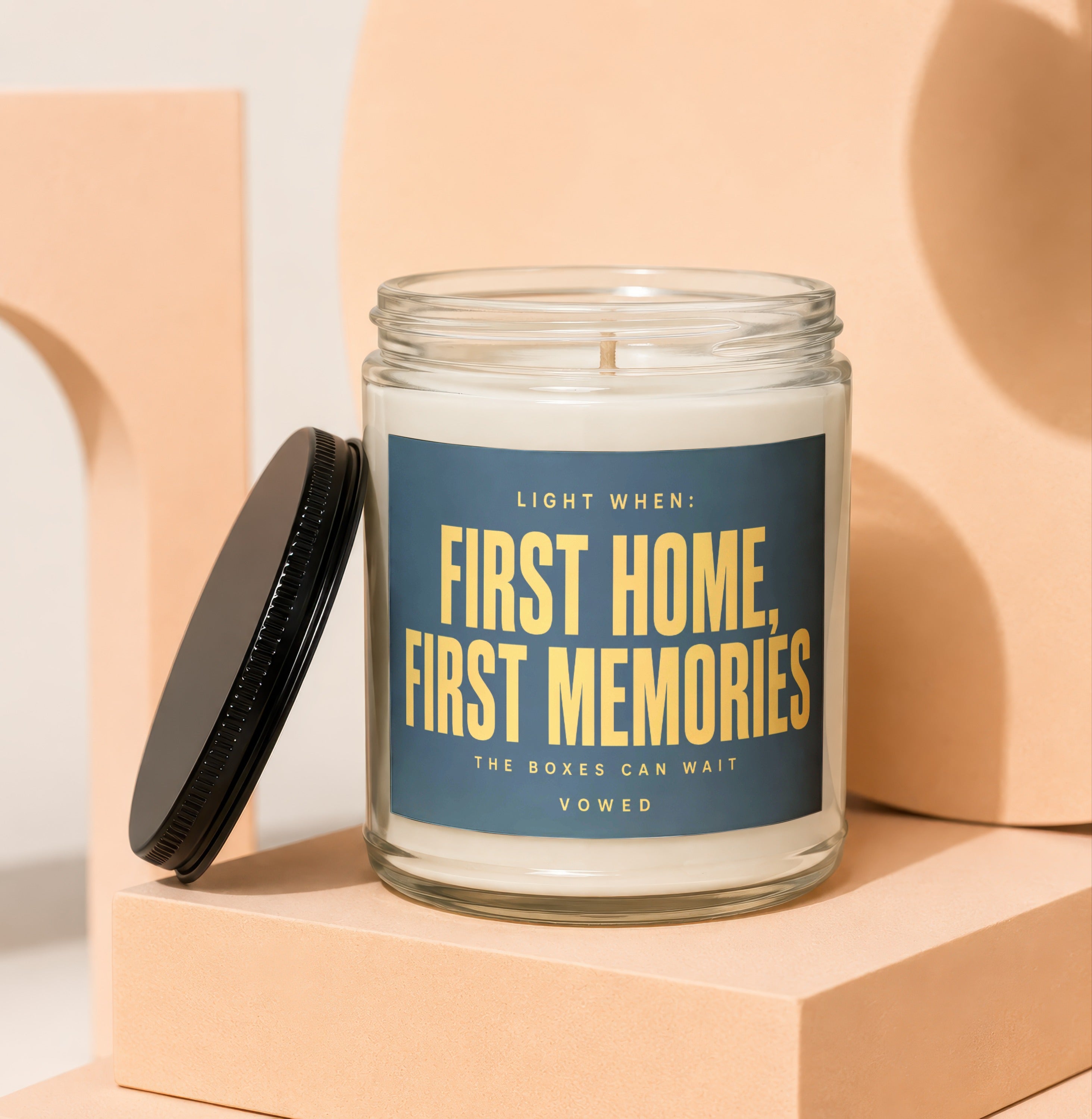 Glass candle with gold text reading "First Home, First Memories", "The Boxes Can Wait", and "Vowed".