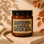 Brown glass candle with label that reads "Smells Like Someone Else's Open Bar".