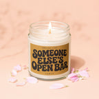 Jar candle with lit flame and label reading "Smells Like Someone Else's Open Bar".
