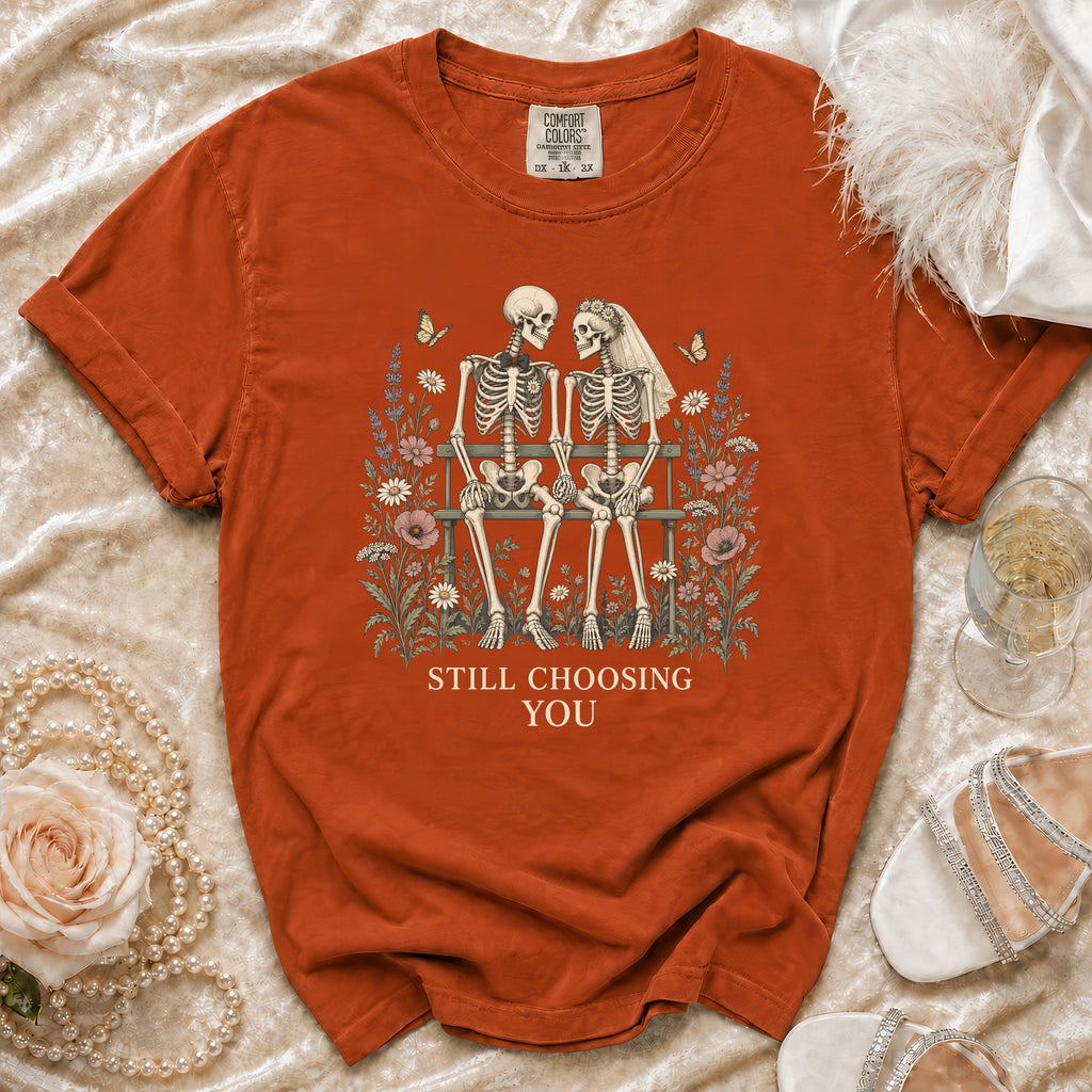 Orange t-shirt with skeleton couple on a bench graphic and "Still Choosing You" text.