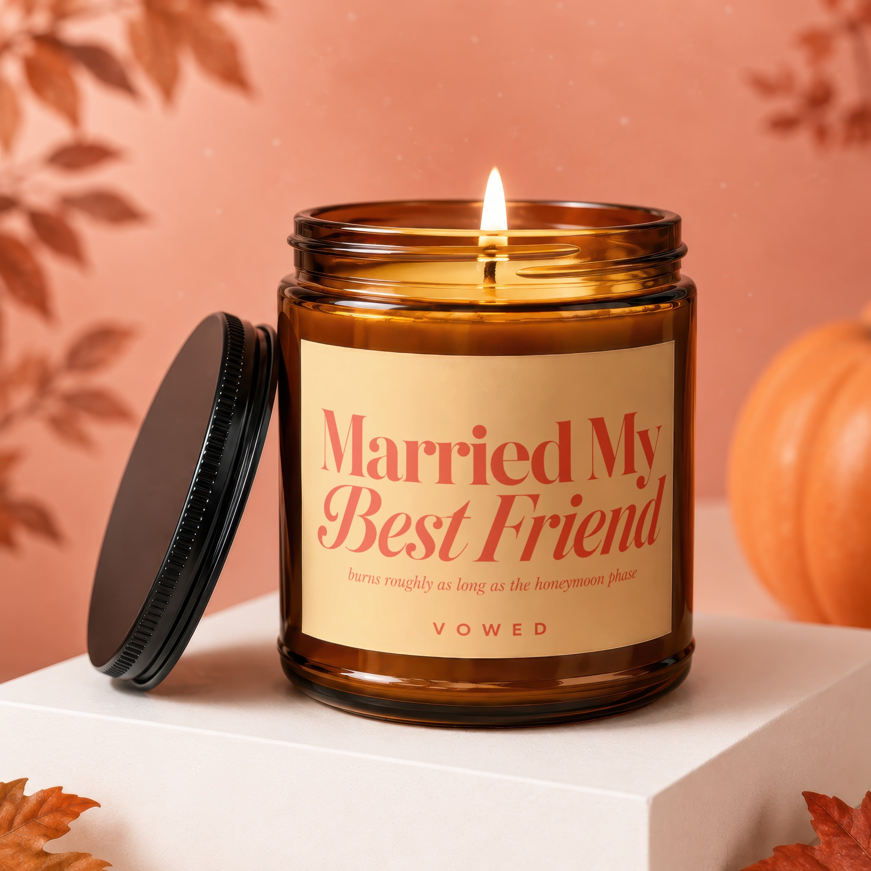 Amber glass candle with lit flame, black lid, and label that reads "Married My Best Friend."