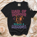 Black t-shirt with "Maid of Honour Needs a Mimosa" text and graphic.