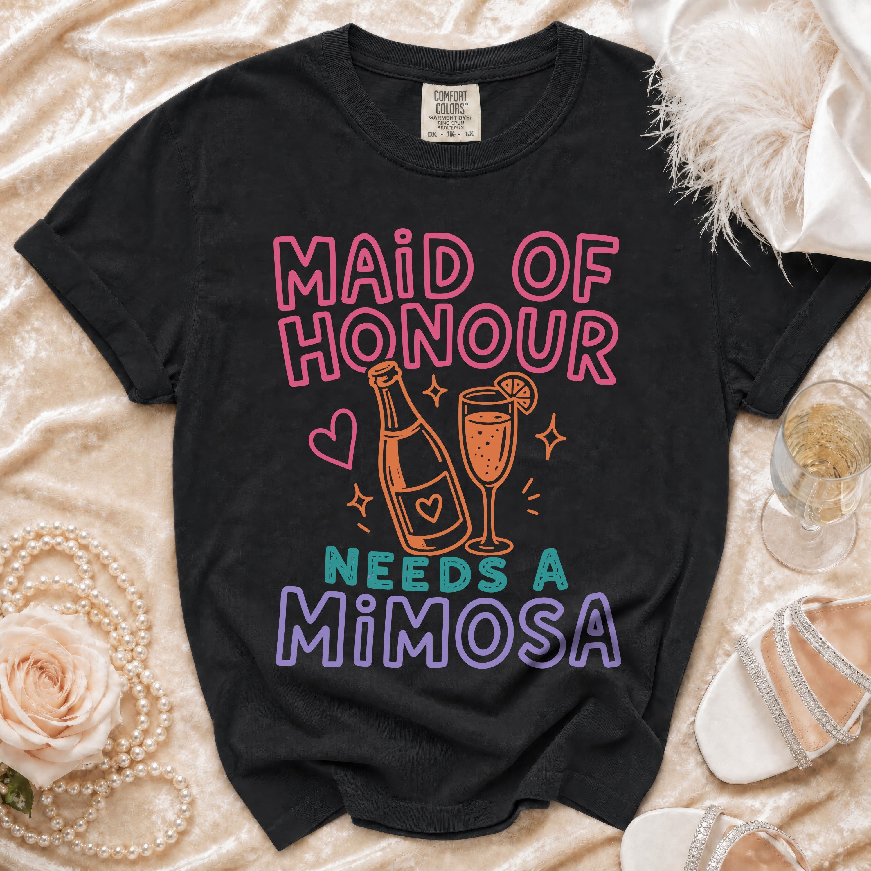 Black t-shirt with "Maid of Honour Needs a Mimosa" text and graphic.