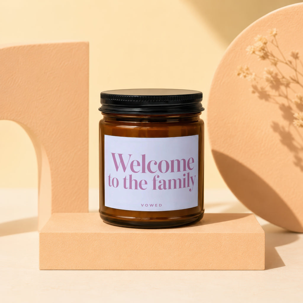 Amber glass candle with "Welcome to the family" text on white label.